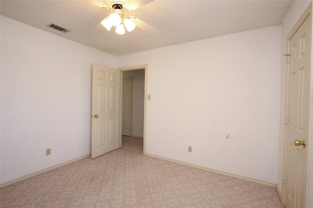 unfurnished bedroom featuring ceiling fan, a textured ceiling, light carpet, visible vents, and baseboards