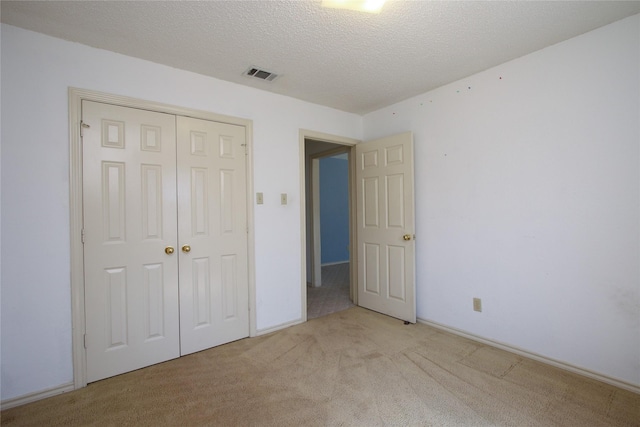 unfurnished bedroom featuring a closet, a textured ceiling, visible vents, and carpet flooring