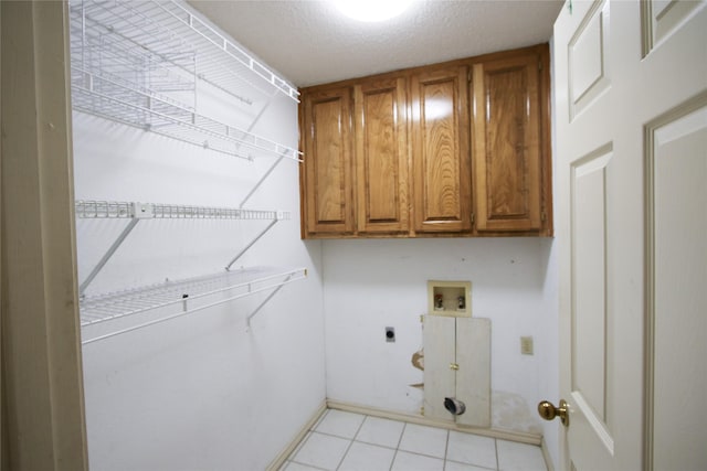 laundry area featuring light tile patterned floors, hookup for a washing machine, cabinet space, and hookup for an electric dryer