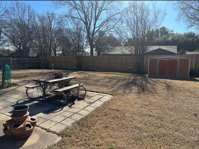 view of yard featuring a patio area, a fenced backyard, a storage unit, and an outdoor structure