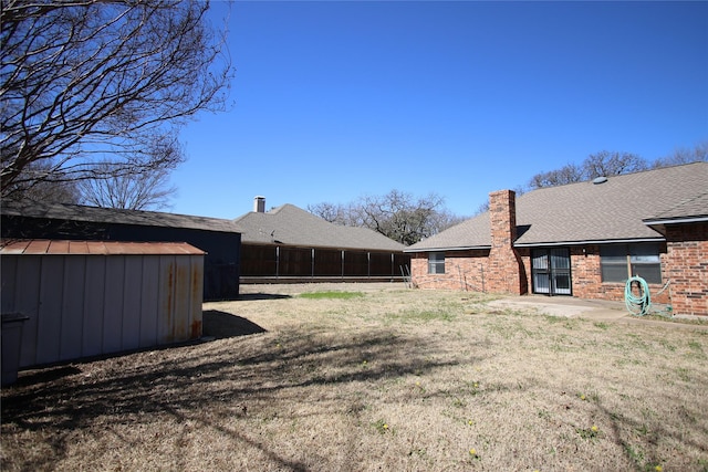 view of yard featuring a storage shed, fence, and an outdoor structure