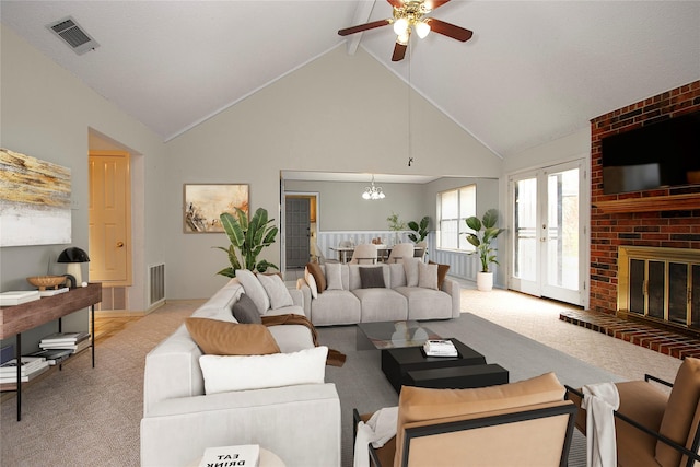 living area with high vaulted ceiling, a brick fireplace, light carpet, and visible vents