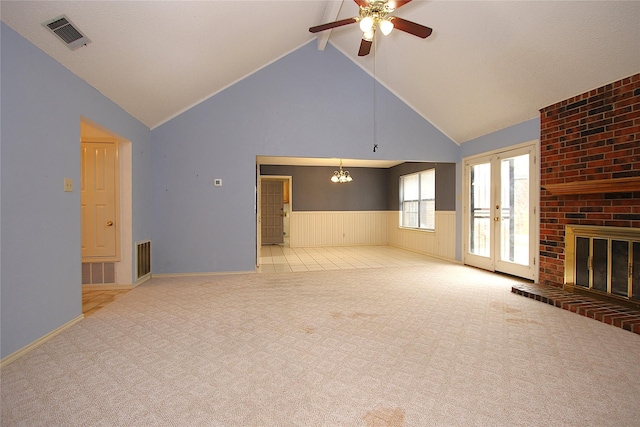 unfurnished living room with a brick fireplace, wainscoting, visible vents, and carpet flooring