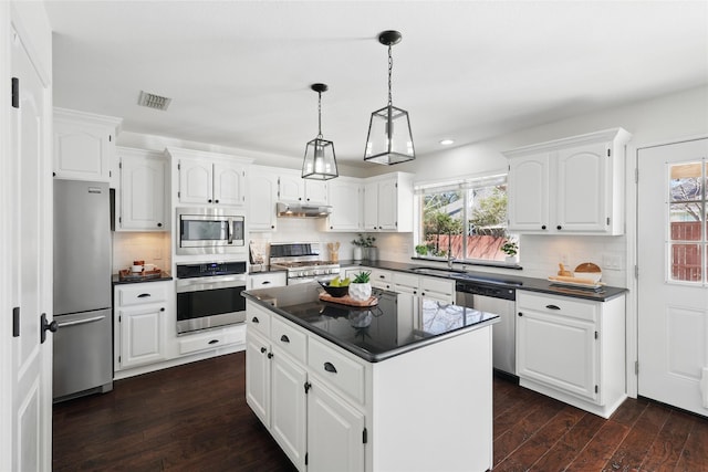 kitchen with under cabinet range hood, stainless steel appliances, visible vents, white cabinets, and dark countertops