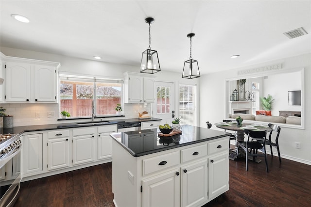 kitchen with dark countertops, stainless steel electric range, dark wood-style flooring, and a sink