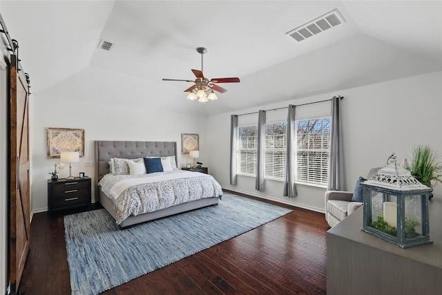 bedroom featuring a barn door, visible vents, and dark wood finished floors