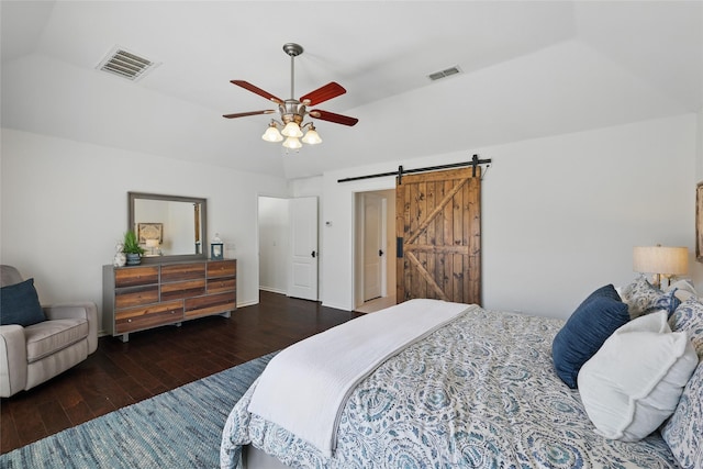 bedroom featuring hardwood / wood-style floors, ceiling fan, a barn door, and visible vents