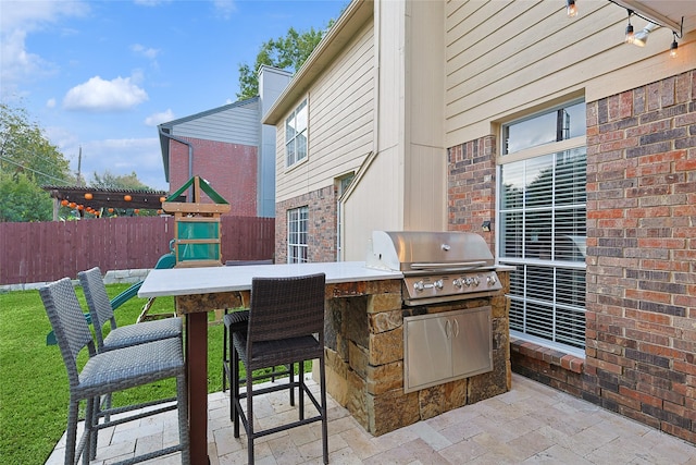 view of patio featuring fence, grilling area, exterior kitchen, and outdoor wet bar