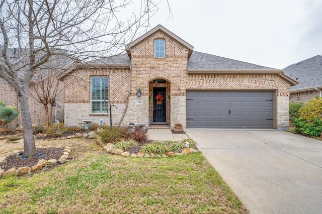 french country style house featuring brick siding, a shingled roof, an attached garage, stone siding, and driveway