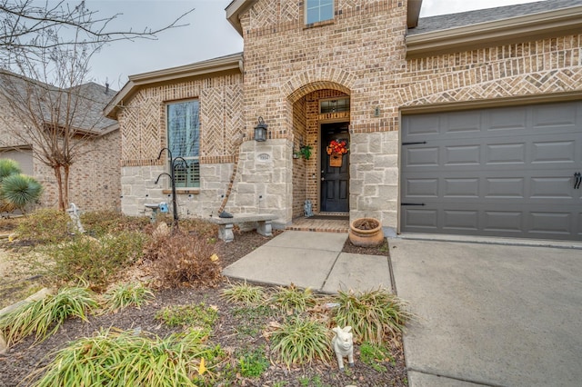 property entrance with a garage, stone siding, driveway, and brick siding