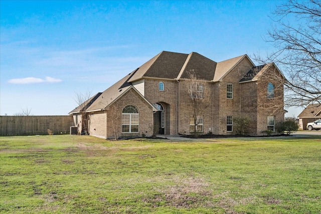 view of front of home with brick siding, fence, and a front yard