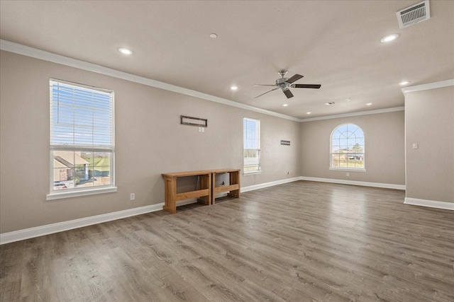 empty room featuring visible vents, ornamental molding, a ceiling fan, wood finished floors, and baseboards