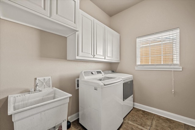 washroom featuring dark tile patterned flooring, baseboards, cabinet space, and washing machine and clothes dryer