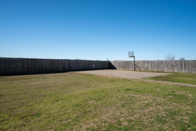 view of yard featuring basketball hoop and fence