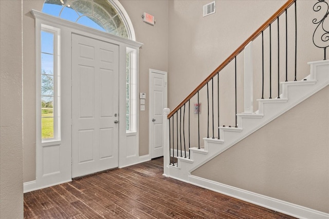 entrance foyer with dark wood-style floors, visible vents, baseboards, and stairs