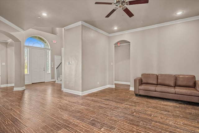 foyer entrance with arched walkways, crown molding, baseboards, and wood finished floors