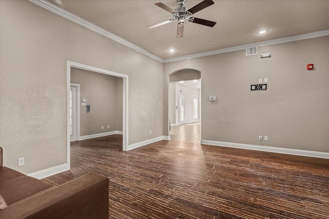 spare room with baseboards, arched walkways, ceiling fan, wood finished floors, and crown molding