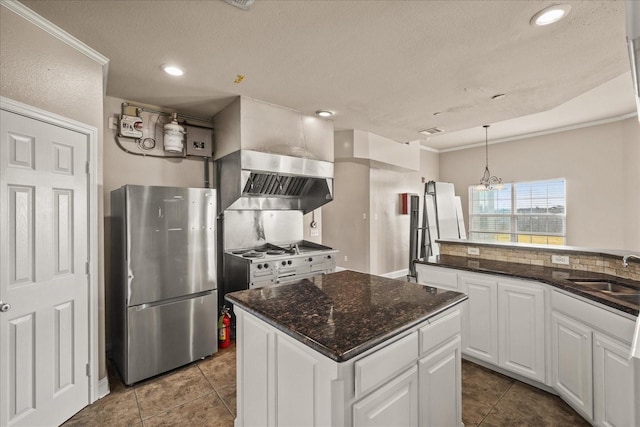 kitchen featuring a kitchen island, a sink, white cabinets, freestanding refrigerator, and wall chimney exhaust hood