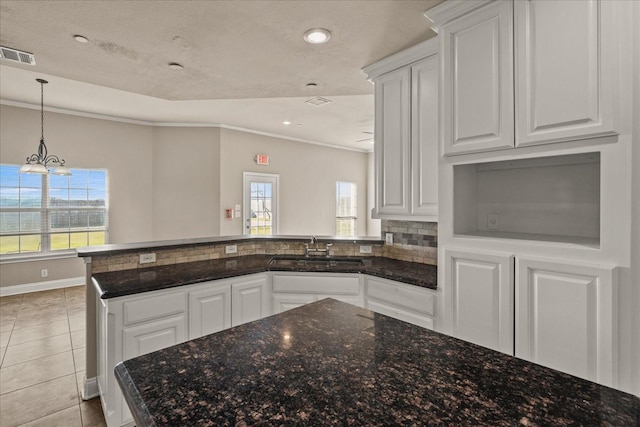 kitchen featuring crown molding, white cabinets, visible vents, and a sink