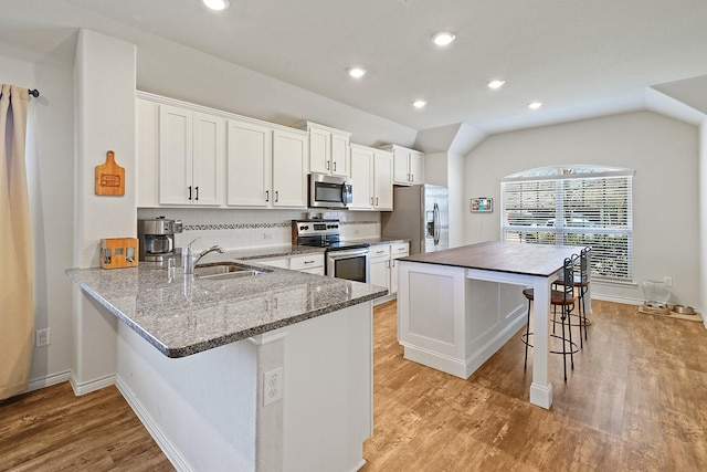 kitchen featuring light wood finished floors, stainless steel appliances, a breakfast bar, and a sink