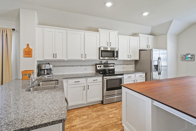 kitchen featuring light wood-style flooring, a sink, white cabinets, appliances with stainless steel finishes, and decorative backsplash