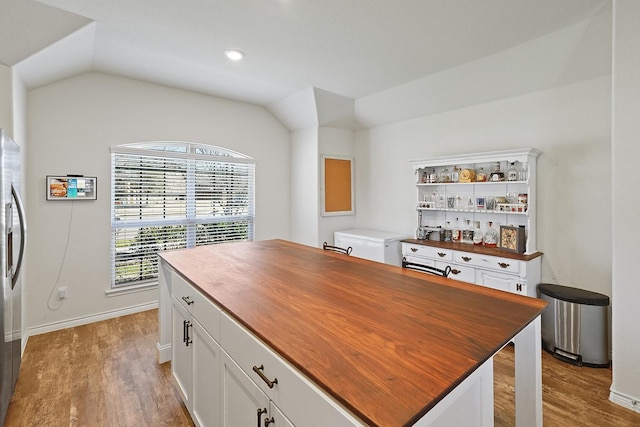 office area with light wood finished floors, baseboards, and vaulted ceiling