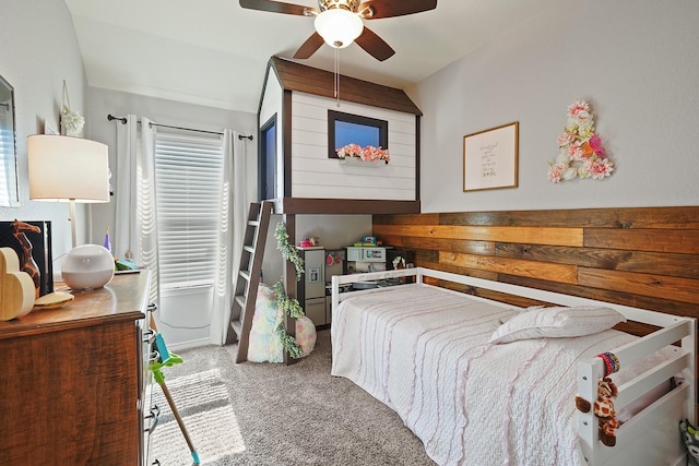 carpeted bedroom with ceiling fan and wooden walls