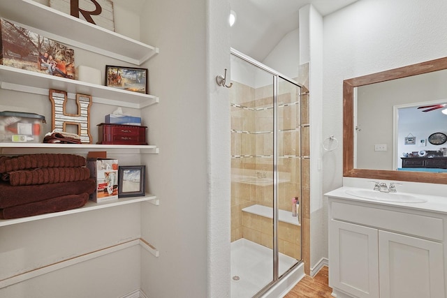 full bath with a stall shower, ceiling fan, vanity, and wood finished floors