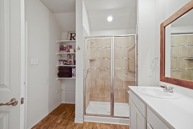 bathroom featuring a shower stall, baseboards, wood finished floors, and vanity