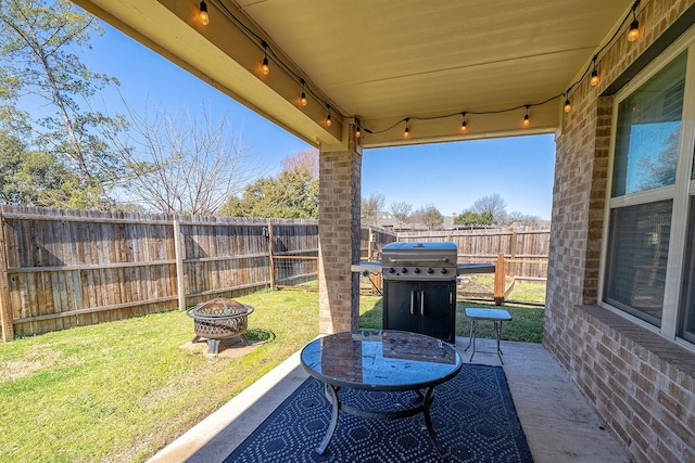 view of patio with an outdoor fire pit, a grill, and a fenced backyard