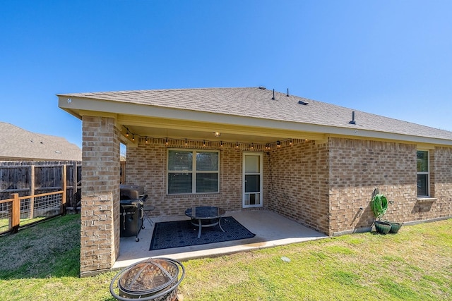 back of property featuring a yard, brick siding, a patio area, and fence