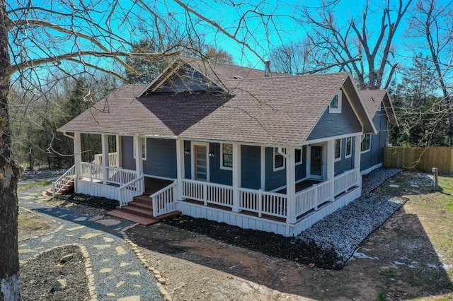 view of front of property with a shingled roof, covered porch, driveway, and fence