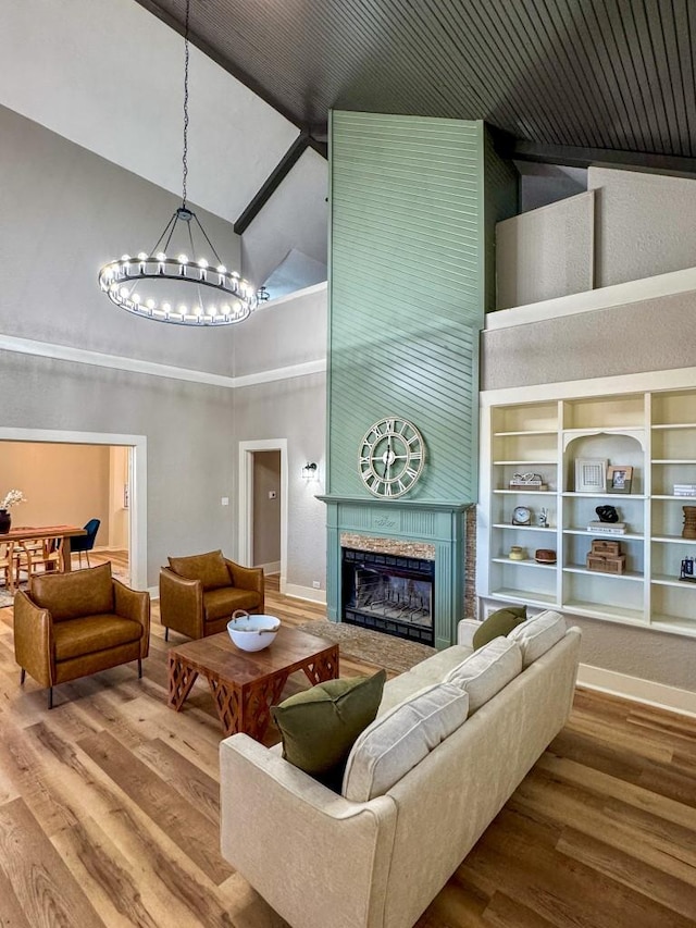 living area featuring a chandelier, high vaulted ceiling, a fireplace, and wood finished floors