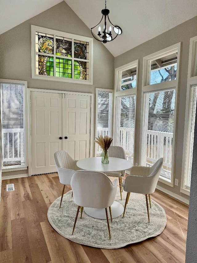 dining space with an inviting chandelier, high vaulted ceiling, and light wood-style floors