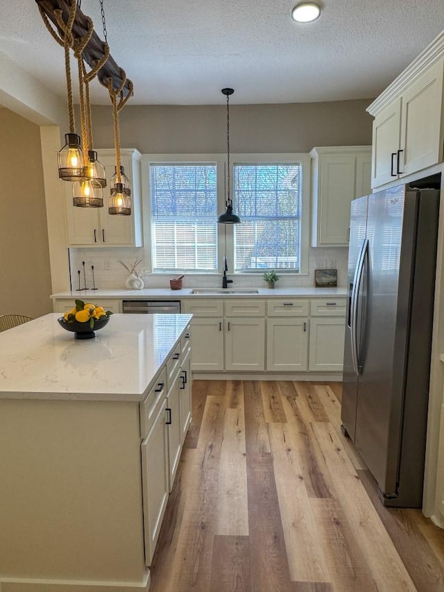 kitchen with a sink, white cabinetry, light wood-type flooring, backsplash, and stainless steel fridge with ice dispenser