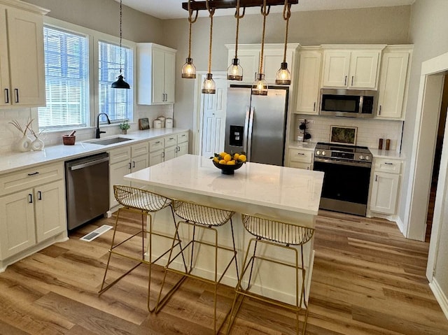 kitchen featuring a sink, visible vents, appliances with stainless steel finishes, light wood finished floors, and tasteful backsplash