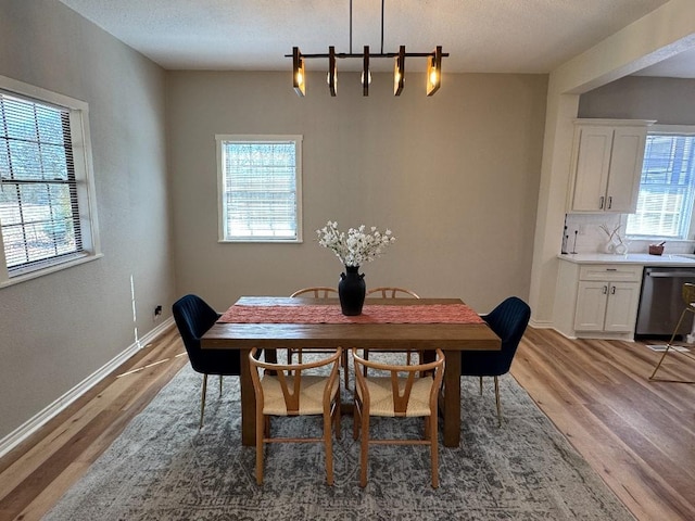 dining room featuring light wood-type flooring, baseboards, and a textured ceiling