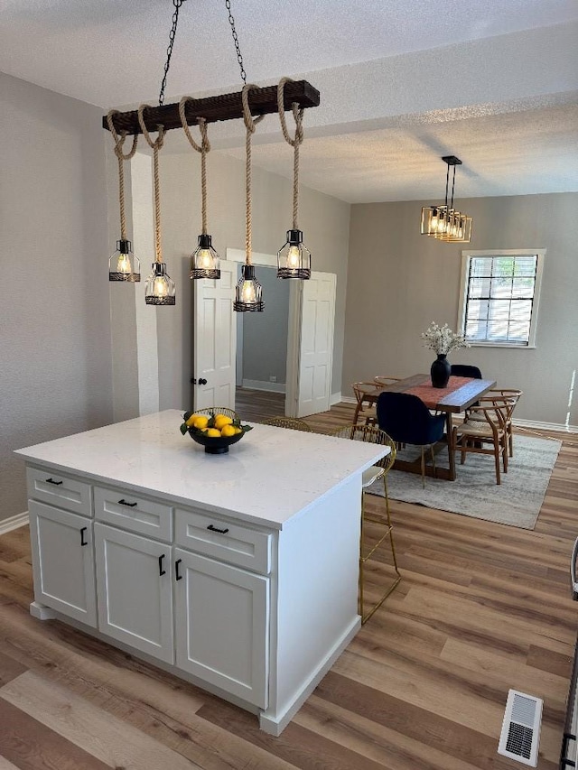 kitchen featuring light countertops, light wood-type flooring, visible vents, and pendant lighting