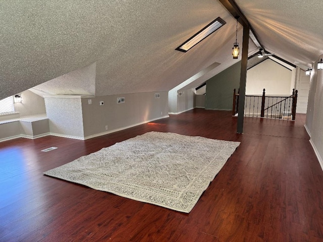 bonus room featuring vaulted ceiling with skylight, baseboards, dark wood finished floors, and a textured ceiling