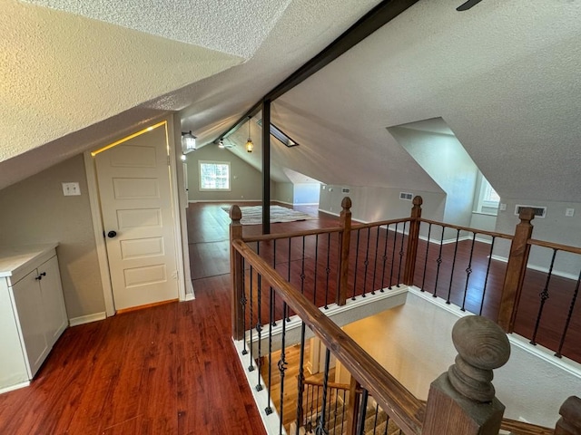 additional living space with ceiling fan, vaulted ceiling, a textured ceiling, wood finished floors, and baseboards