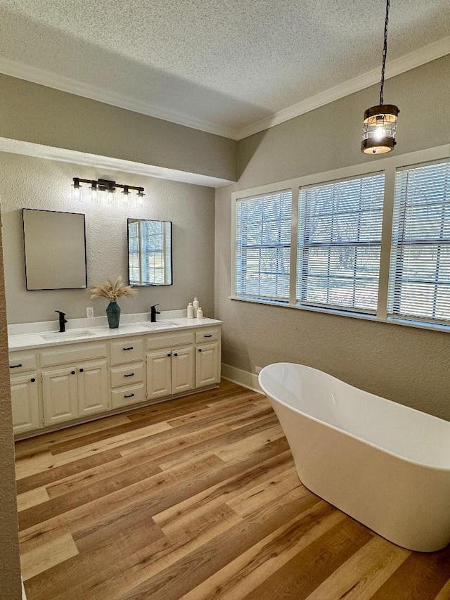 full bathroom featuring ornamental molding, a freestanding tub, a sink, and wood finished floors