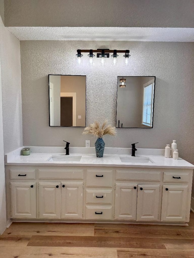 full bath featuring double vanity, a sink, and wood finished floors