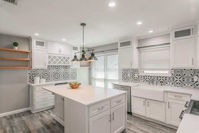 kitchen featuring white cabinets, wood finished floors, light countertops, stainless steel dishwasher, and a sink