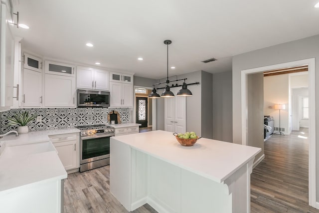 kitchen featuring white cabinets, a kitchen island, stainless steel appliances, light countertops, and a sink