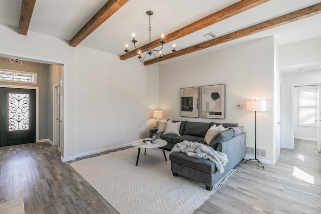 living area with wood finished floors, visible vents, beam ceiling, and an inviting chandelier