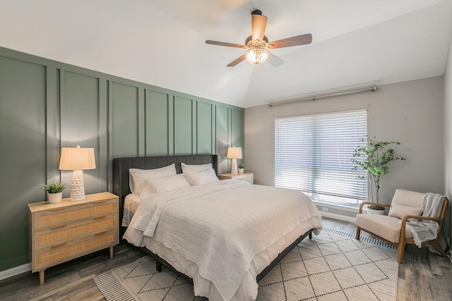 bedroom featuring ceiling fan, lofted ceiling, a decorative wall, and wood finished floors