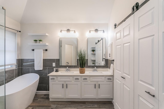 full bath featuring vaulted ceiling, a sink, a freestanding bath, and wood finished floors