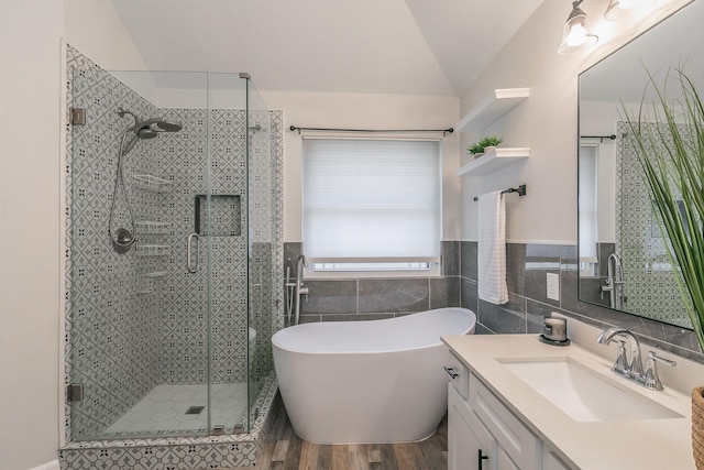 bathroom featuring tile walls, a freestanding bath, a shower stall, vanity, and wood finished floors