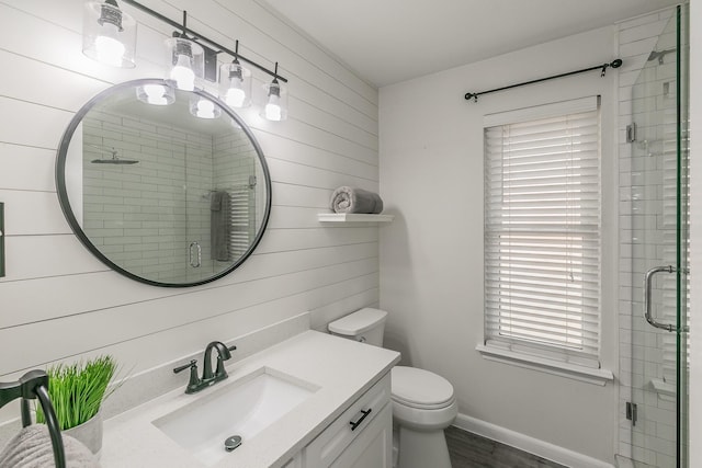 bathroom with wooden walls, baseboards, toilet, vanity, and a shower stall