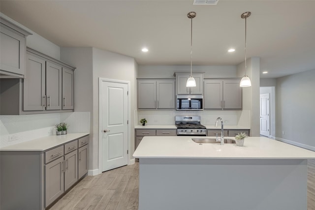 841 Holler Loop, Fort Worth, TX 76247 - kitchen with stainless steel appliances, gray cabinetry, a sink, light wood-style flooring, and tasteful backsplash